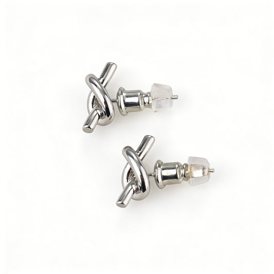 Close-up of 925 silver stud earrings post on a dainty gold knot earring, hypoallergenic jewelry.