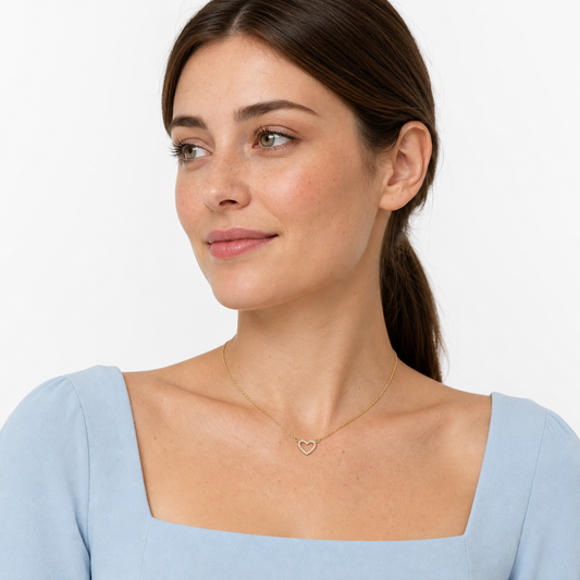 Three-quarter portrait of a young woman wearing a delicate gold-tone CZ open heart necklace.