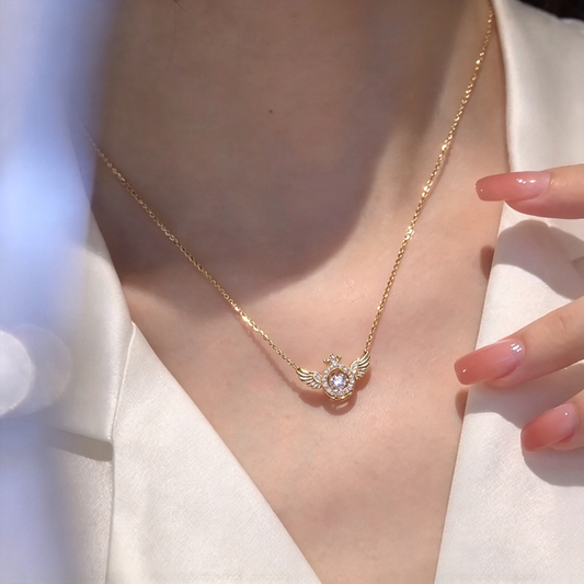 Close-up of the angel wing necklace worn at the neckline, showing the round pendant and wing details.