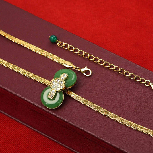 Flat lay of Chinoiserie vintage green crystal double donut herringbone necklace showcasing its smooth, liquid-gold flat snake chain and secure clasp.