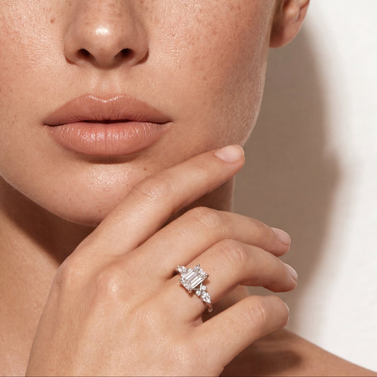 Portrait of a freckled model with smoky makeup wearing a three-stone emerald cut diamond ring with trillion side stones.