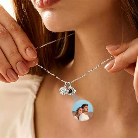 Close-up view of the seashell charms and round photo pendant held up on a delicate necklace chain.