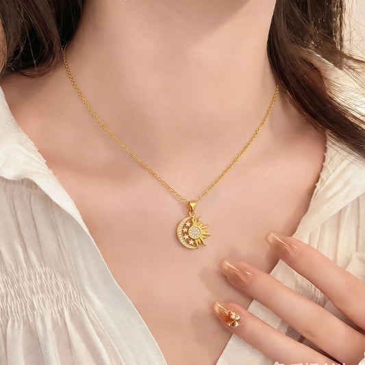 A sun and moon pendant necklace worn at the neckline with a white outfit, showing its placement and scale.