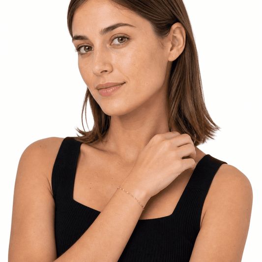 Woman wearing a gold flat link stainless steel bracelet in a white-studio portrait