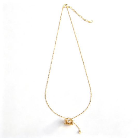Full product shot of a gold filigree floral lock tassel pendant necklace displayed on a white background.