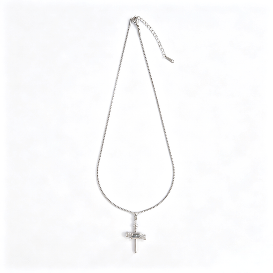 Angled close-up of industrial nail cross pendant showing glossy silver finish