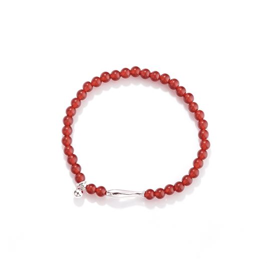 Top view of a red agate beaded stretch bracelet with a silver-tone koi centerpiece and round dangle charm.