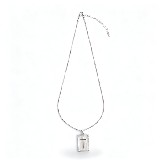 Full length view of a silver-tone rectangular cross pendant necklace laid out on a white surface.