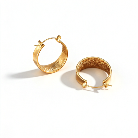 A pair of oval hoop earrings shown at an angle, highlighting the textured inner surface and hinged closures