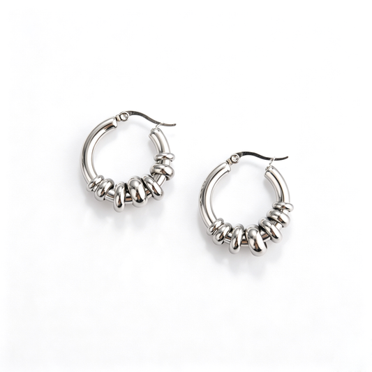 Top-down view of polished stainless steel multi-ring movable bead hoop earrings on white background.