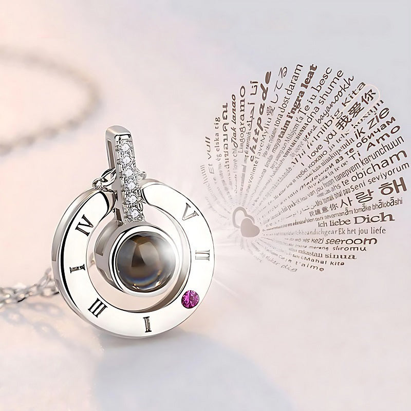 Round pendant with Roman numeral details displayed beside a heart-shaped graphic surrounded by multilingual text.