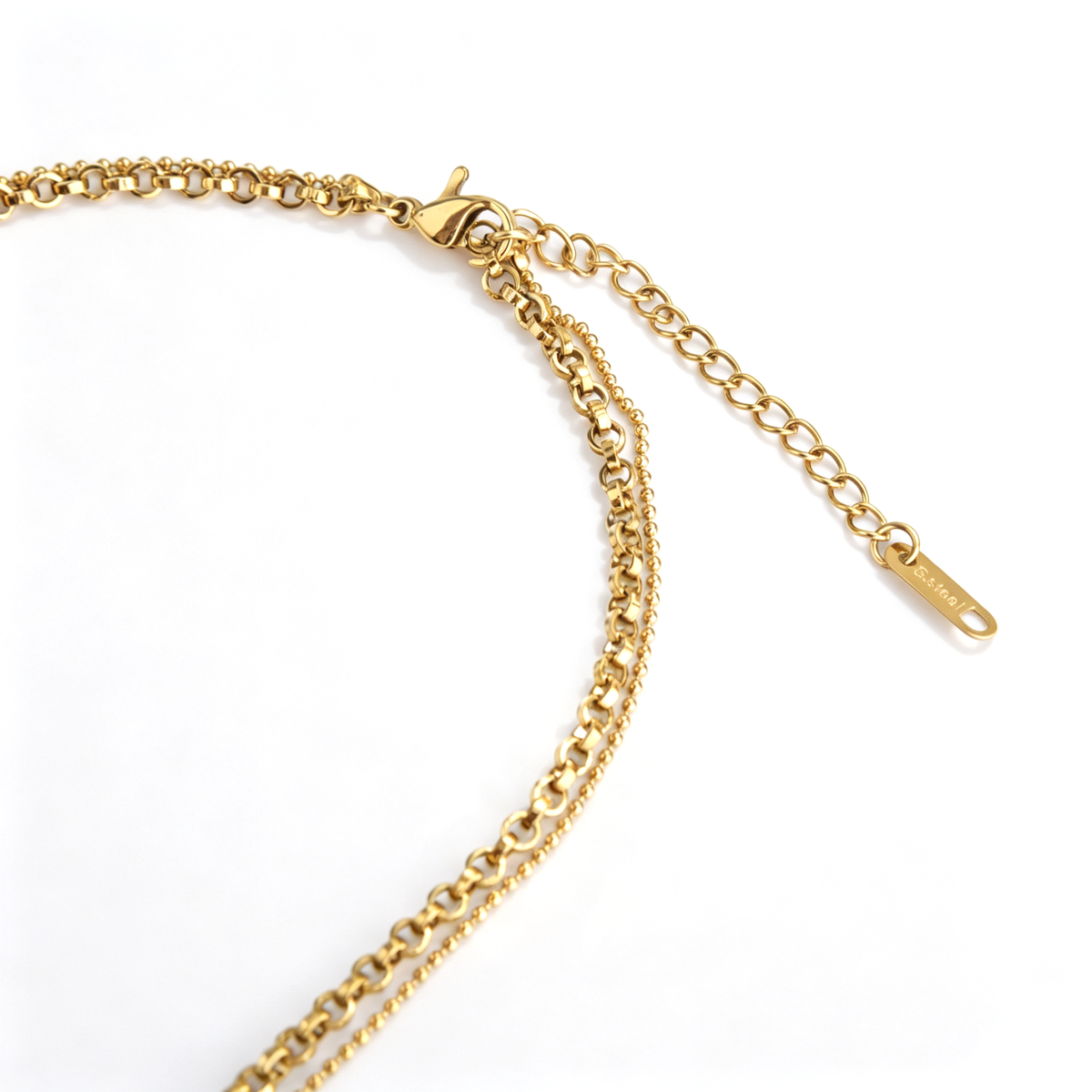 Close-up of the lobster claw clasp and extension chain connecting both strands of a gold layered necklace.