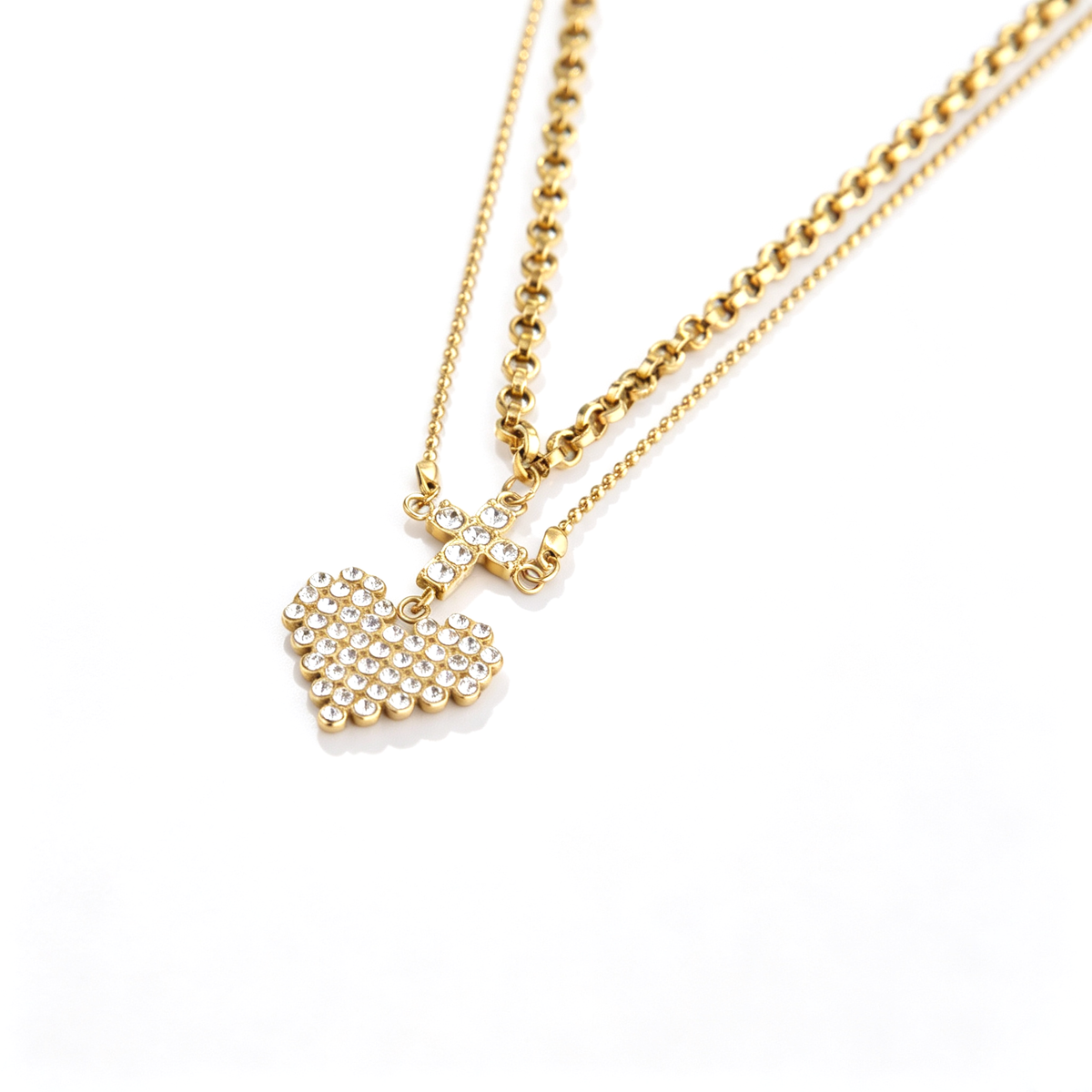 Close-up perspective of the pavé cubic zirconia cross and heart pendant on a gold double-layer chain.