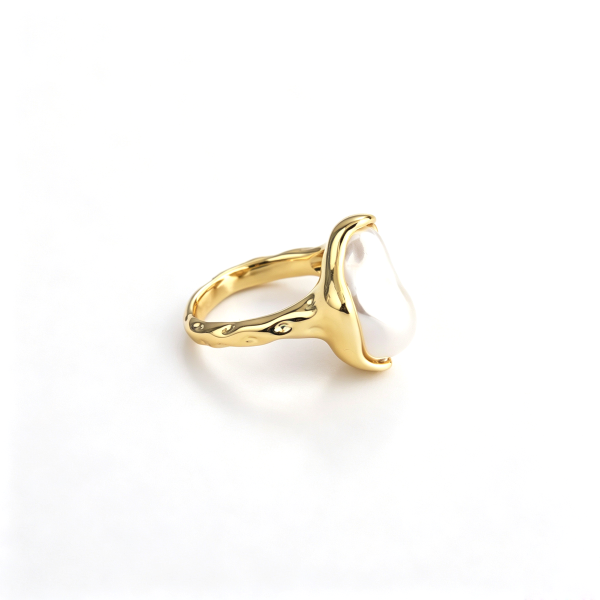 Profile angle highlighting the liquid molten metal bezel encasing an irregular white pearl.