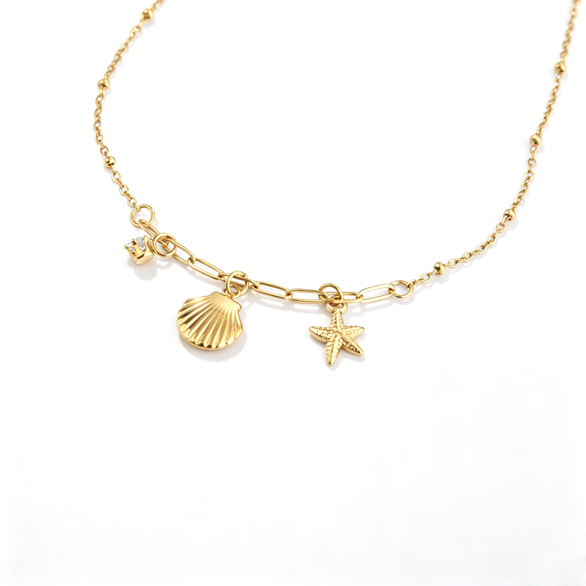 Detail view of 18k gold-plated charms including a textured seashell, starfish, and zircon drop.