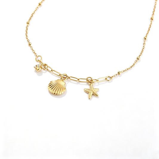Detail view of 18k gold-plated charms including a textured seashell, starfish, and zircon drop.