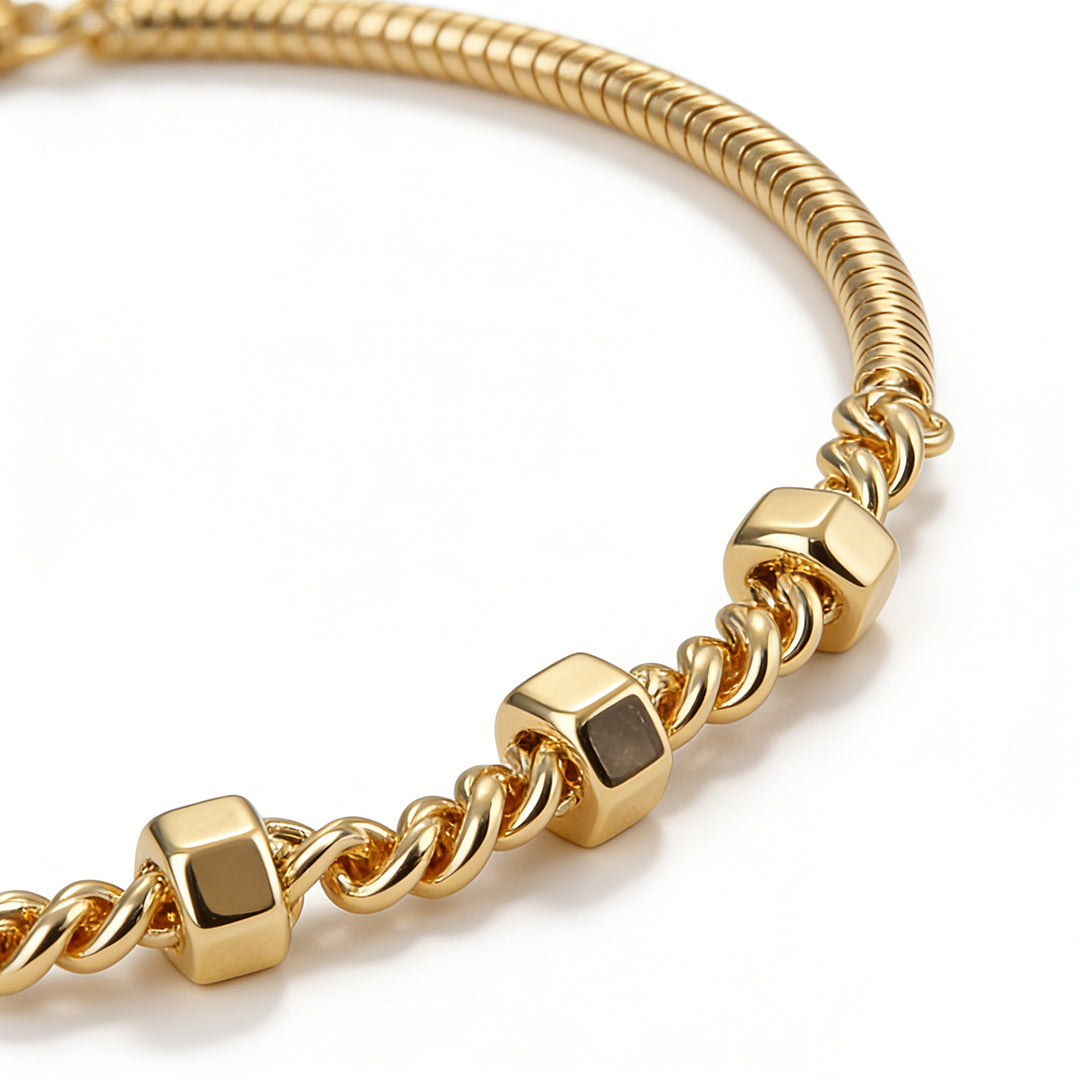 Macro shot of the smooth snake chain texture and high-shine 18k gold plating on a mixed-link bracelet.