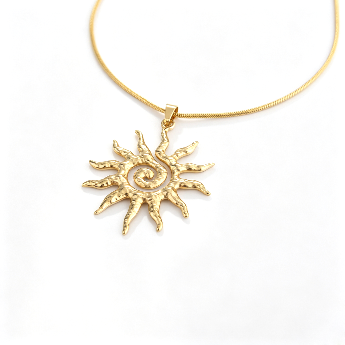 Perspective view showing the textured 18k gold-plated spiral sun pendant on a smooth snake chain.