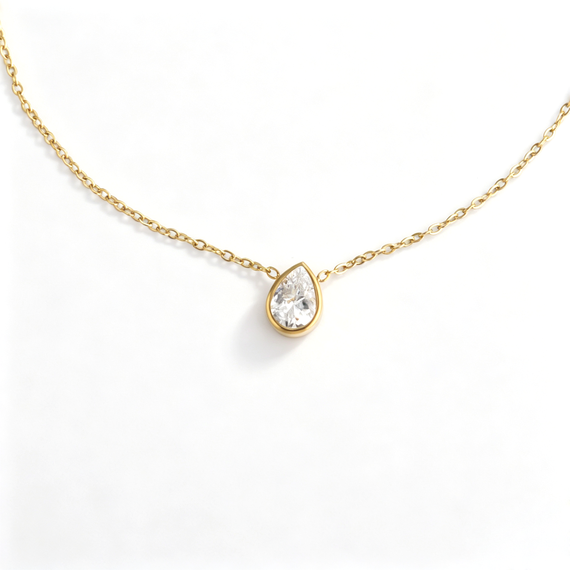 Close-up view of 18k gold bezel set pear-cut CZ pendant with delicate fine link chain