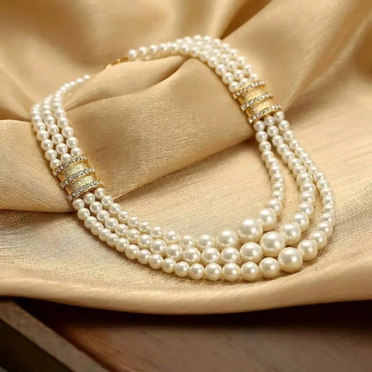 Perspective view of Ever P. vintage inspired triple strand pearl collar necklace nestled on elegant draped silk fabric.