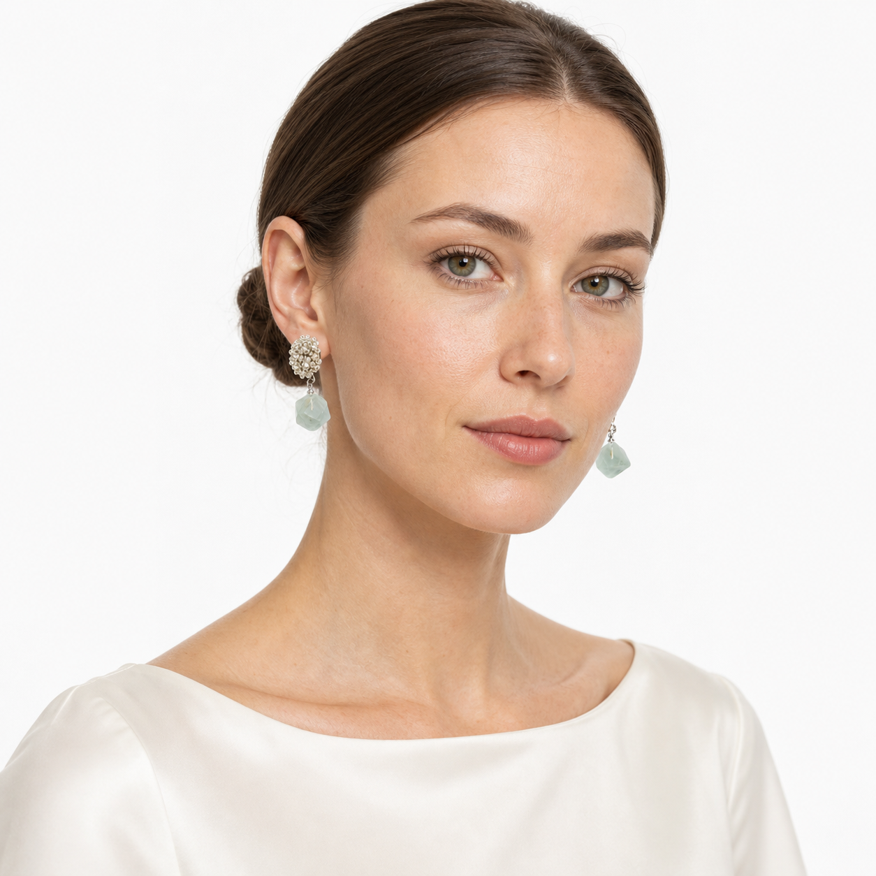 Western woman in a three-quarter white-studio portrait wearing beaded-top green aventurine drop earrings.