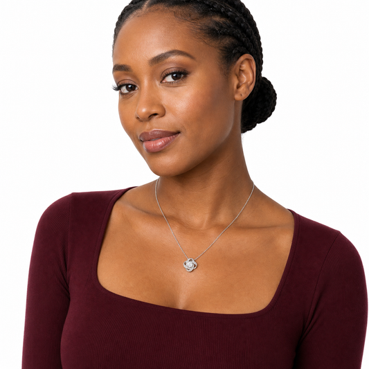 Three-quarter portrait of a Black woman wearing a classic silver-tone love knot cubic zirconia pendant necklace.
