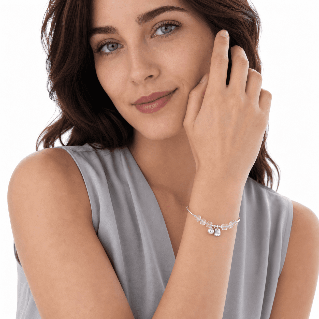 Woman posing with a clear crystal adjustable bracelet featuring geometric beads and two silver-tone dangles.