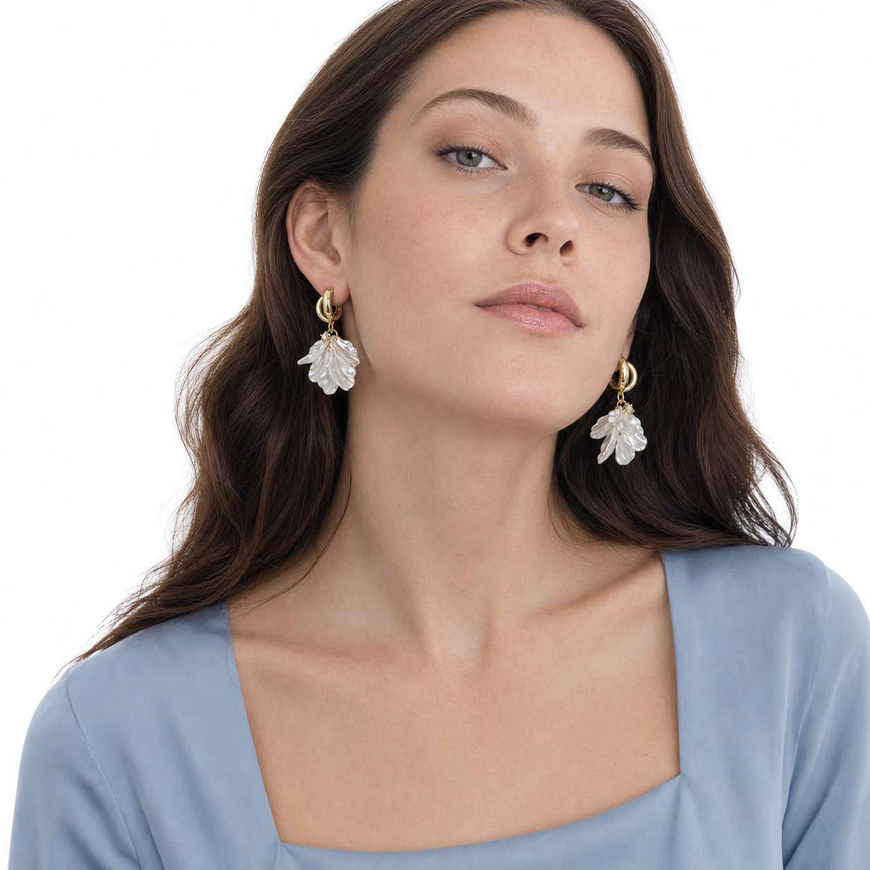 Young long-haired woman in a chin-raised white-studio pose wearing French vintage pearlescent petal hoop earrings.