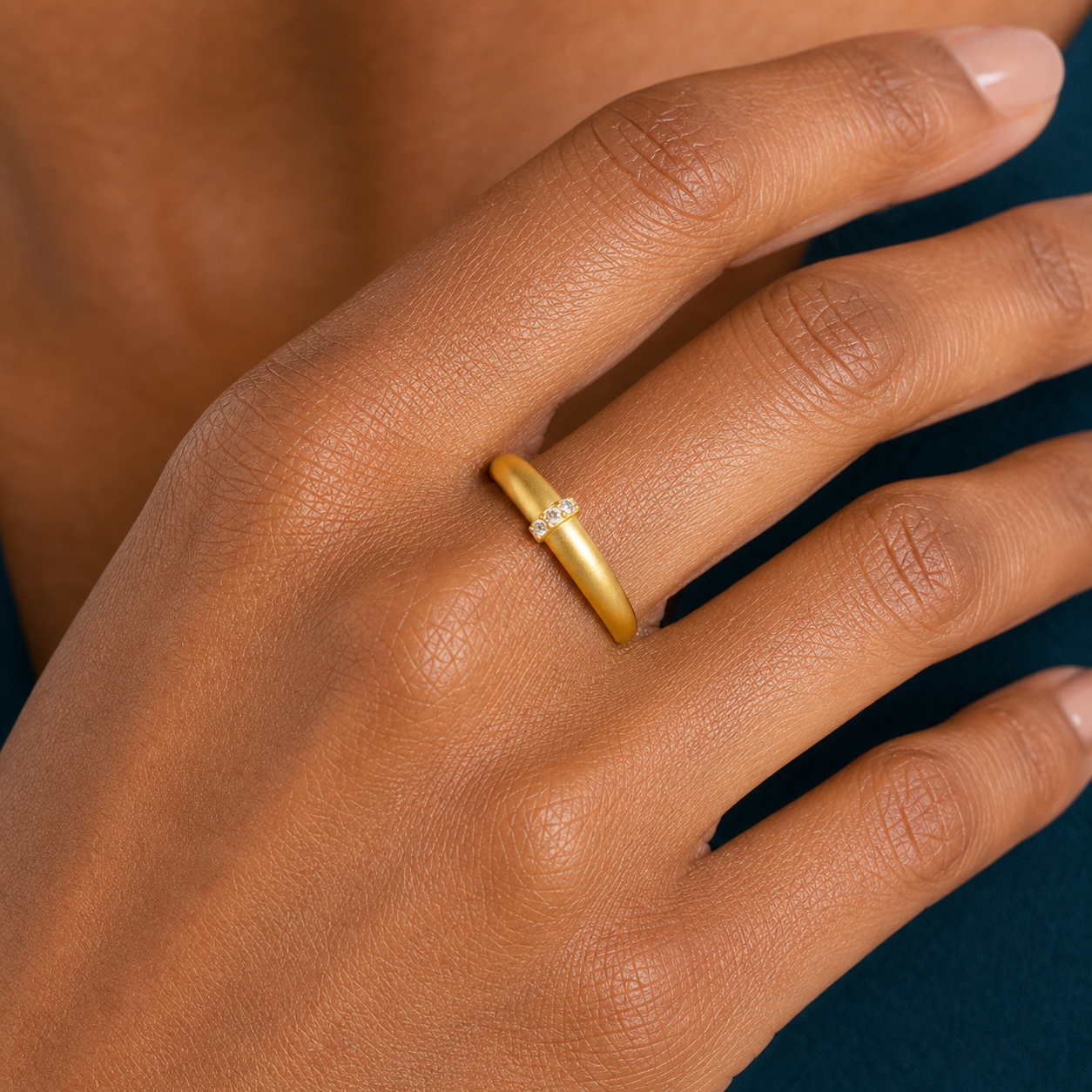 Macro view of a matte gold-tone adjustable ring with a centered row of clear zircon stones.