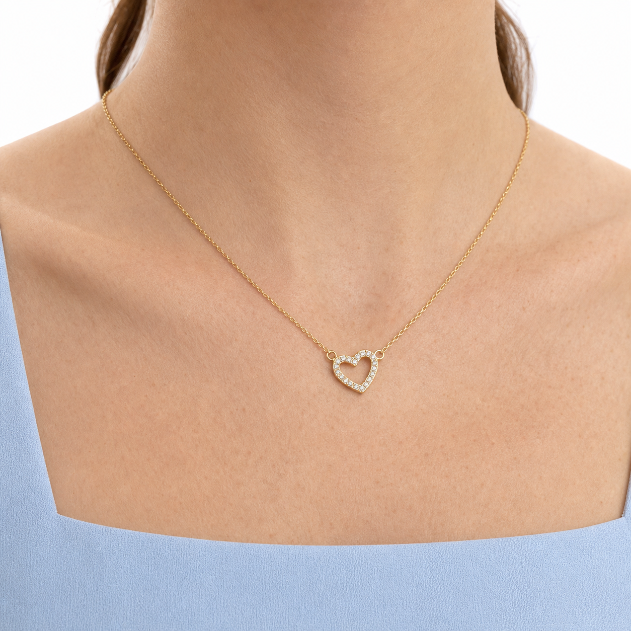Close-up of a gold-tone cubic zirconia open heart centerpiece connected to a fine O-link chain.