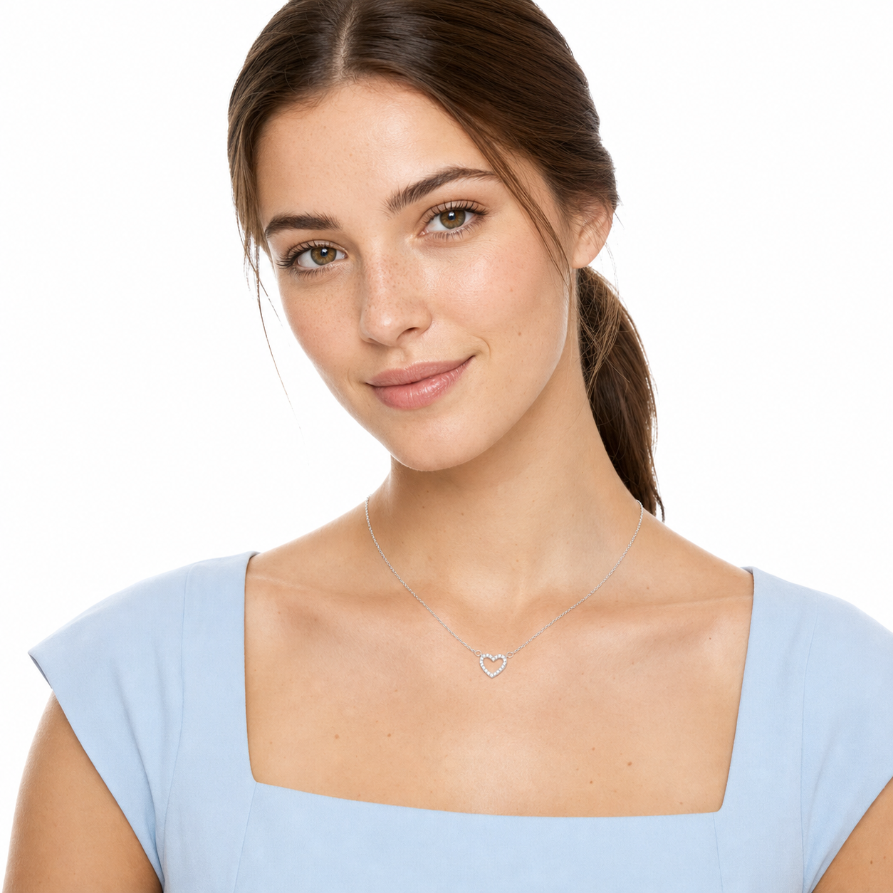 Young woman in a powder-blue top wearing a silver-tone micro-pavé cubic zirconia open heart necklace.