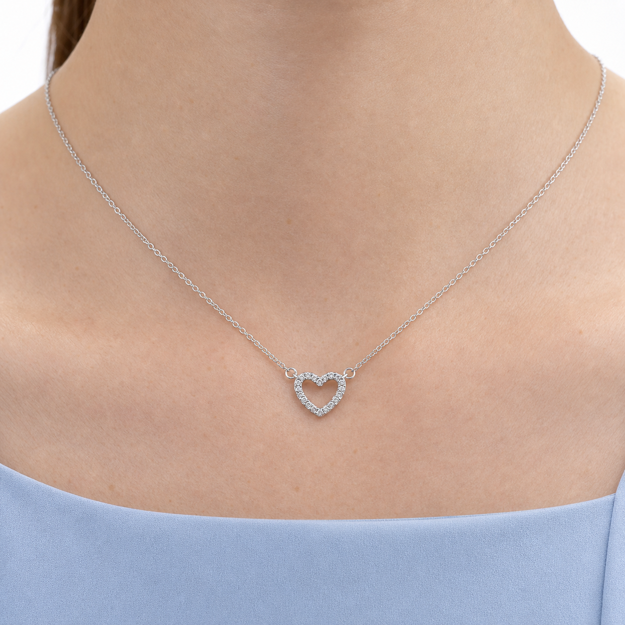 Close-up of a silver-tone cubic zirconia open heart centerpiece connected to a fine O-link chain.
