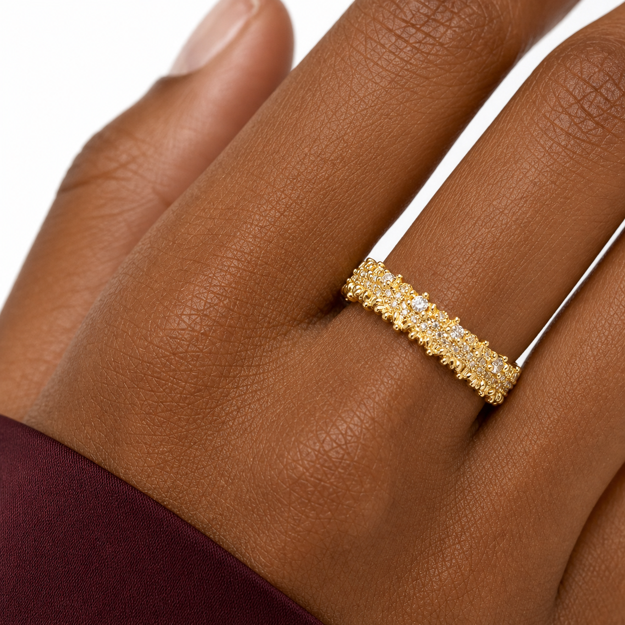 Macro view of a gold-tone cubic zirconia band ring with ornate bead-set pavé detailing.
