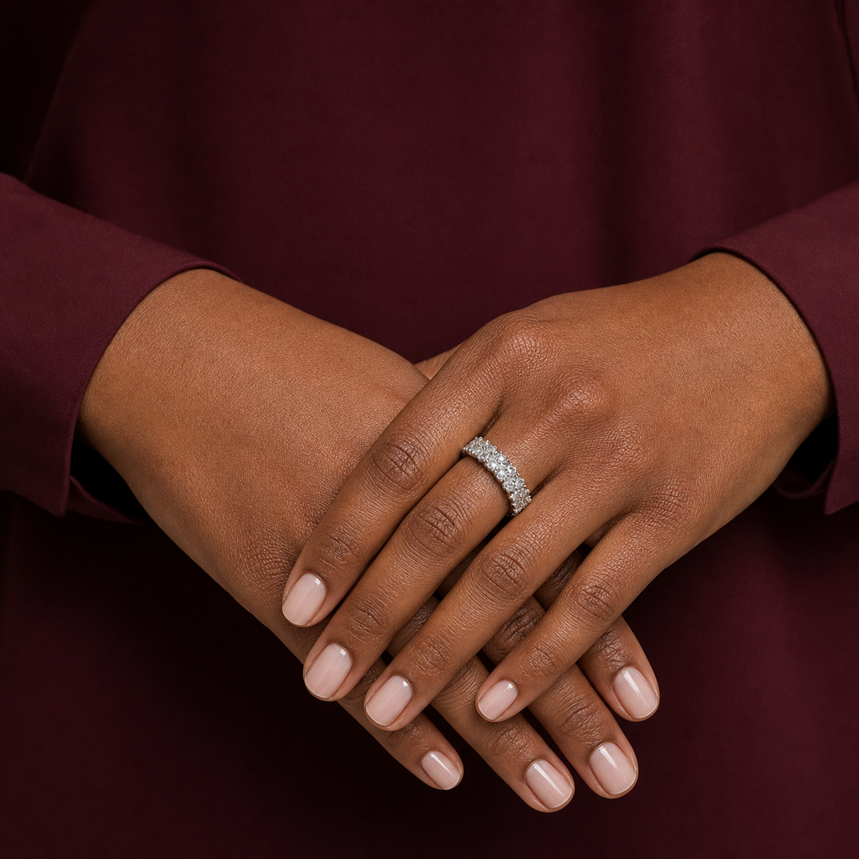 Top-down hand detail of a silver-tone adjustable pavé ring with mixed-size clear cubic zirconia.