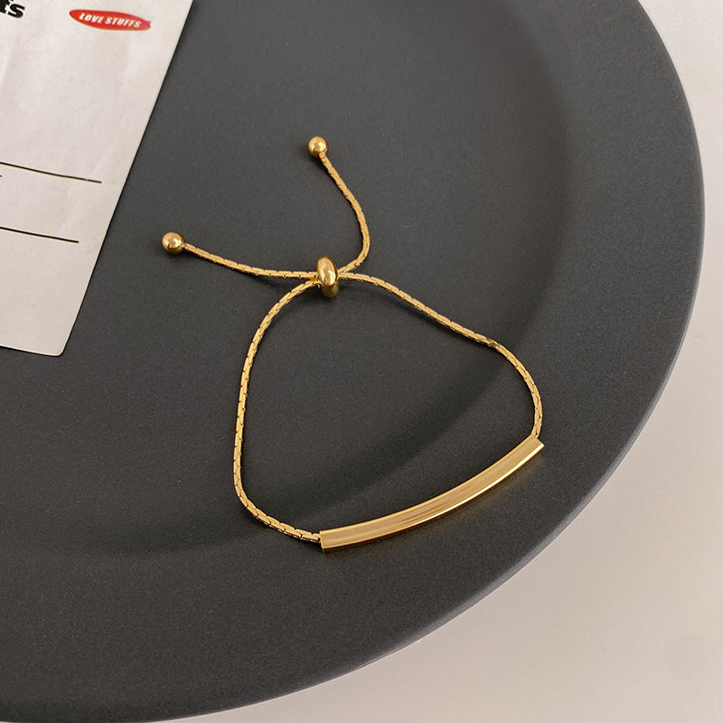 Adjustable bracelet arranged in an oval on a dark display surface, showing the pull cords and bead ends.