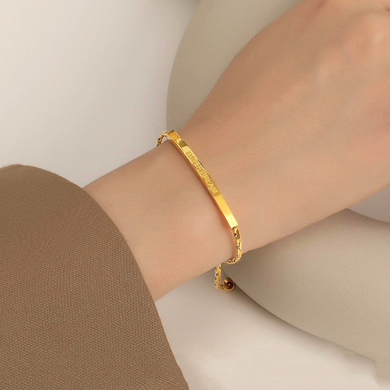 Close-up of the adjustable bar bracelet worn on a wrist against a beige background.