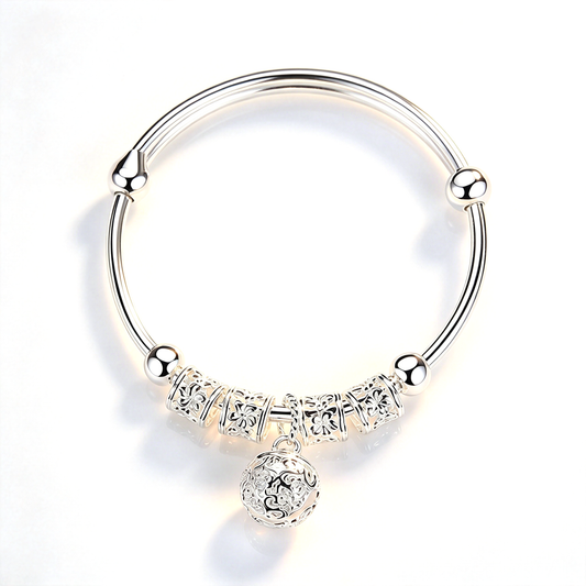 Bell charm bangle bracelet with ornate decorative details and a dangling round charm, shown against a white background