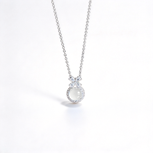 Close-up of a round white pendant framed by small decorative accents beneath a detailed bow design.