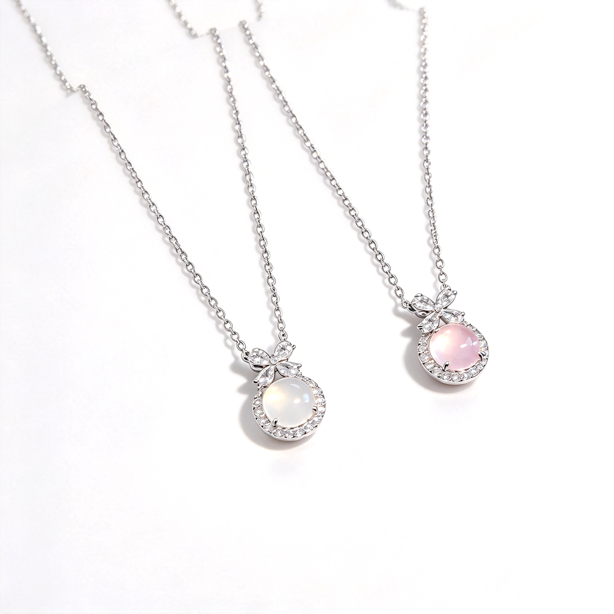 Two bow pendant necklaces displayed side by side with white and pink round centerpieces.