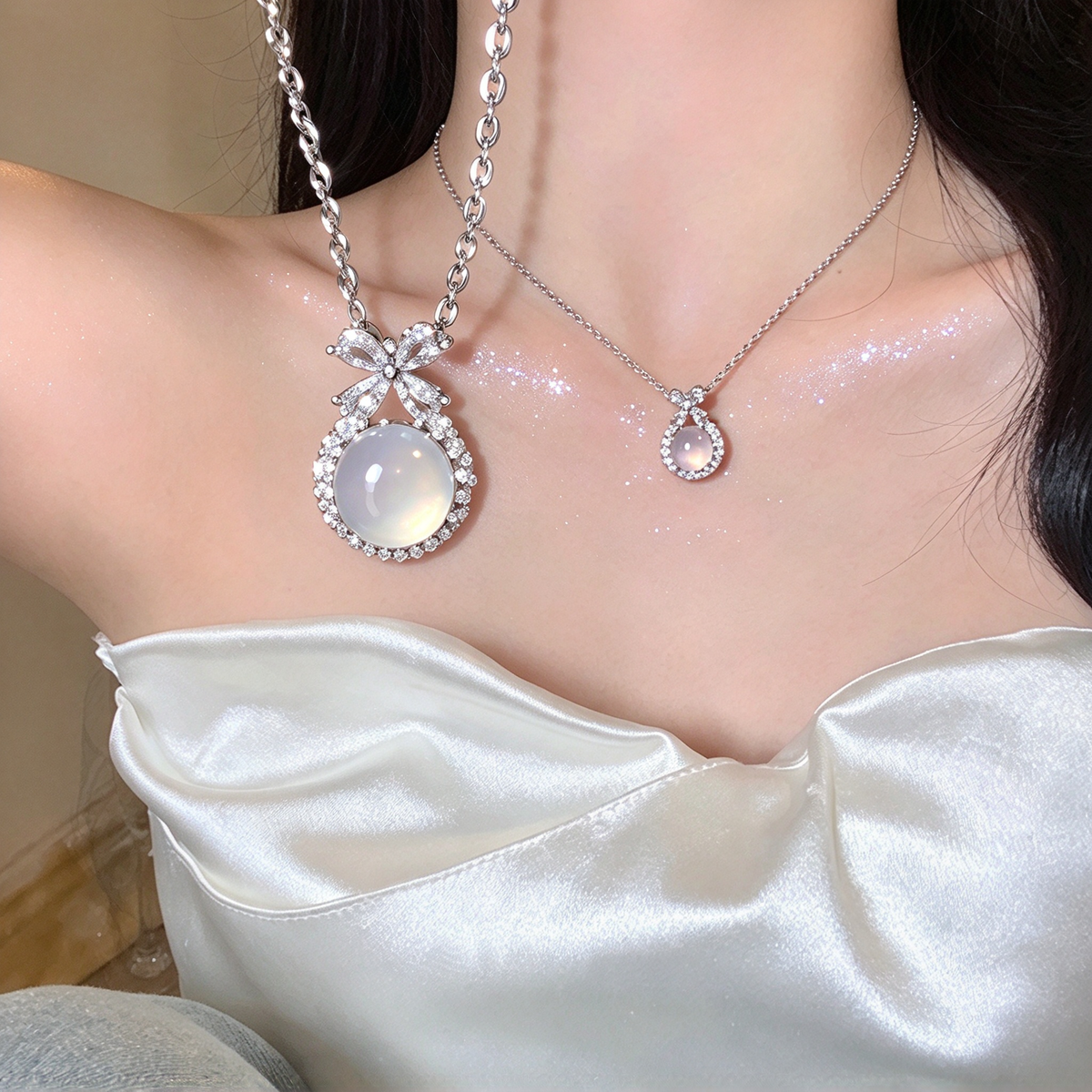 Bow pendant necklace worn with a white strapless top, showing the pendant's position near the neckline.