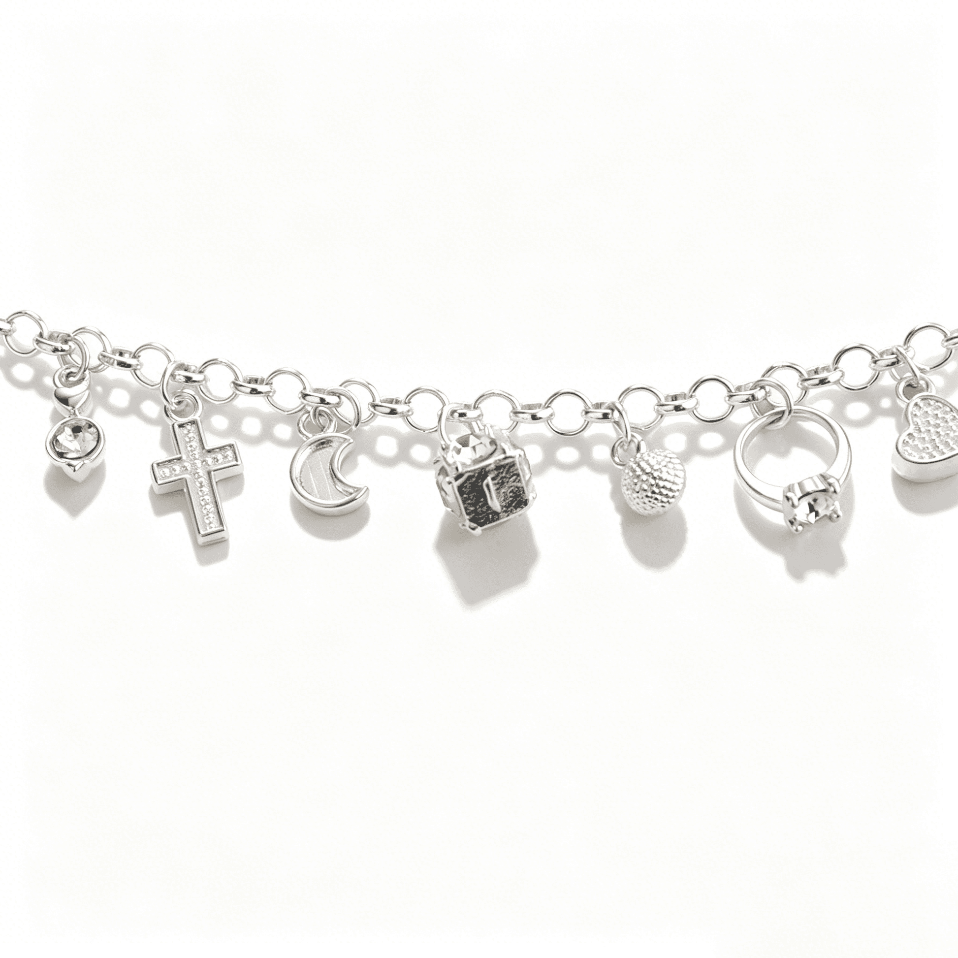 Close-up view of a charm bracelet for women featuring micro pave cross, moon, and heart pendants on a rolo chain.