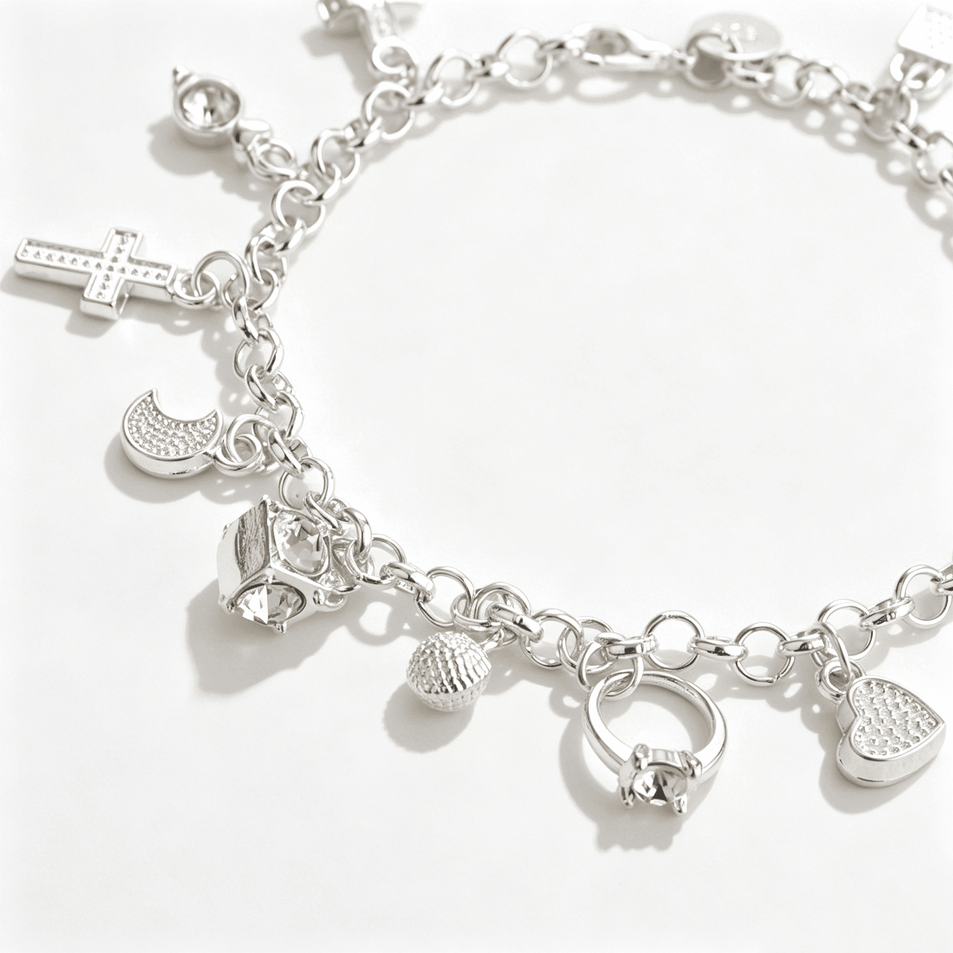A low-angle shot highlighting the brilliant cubic zirconia accents on various pendants of a charm bracelet for women.