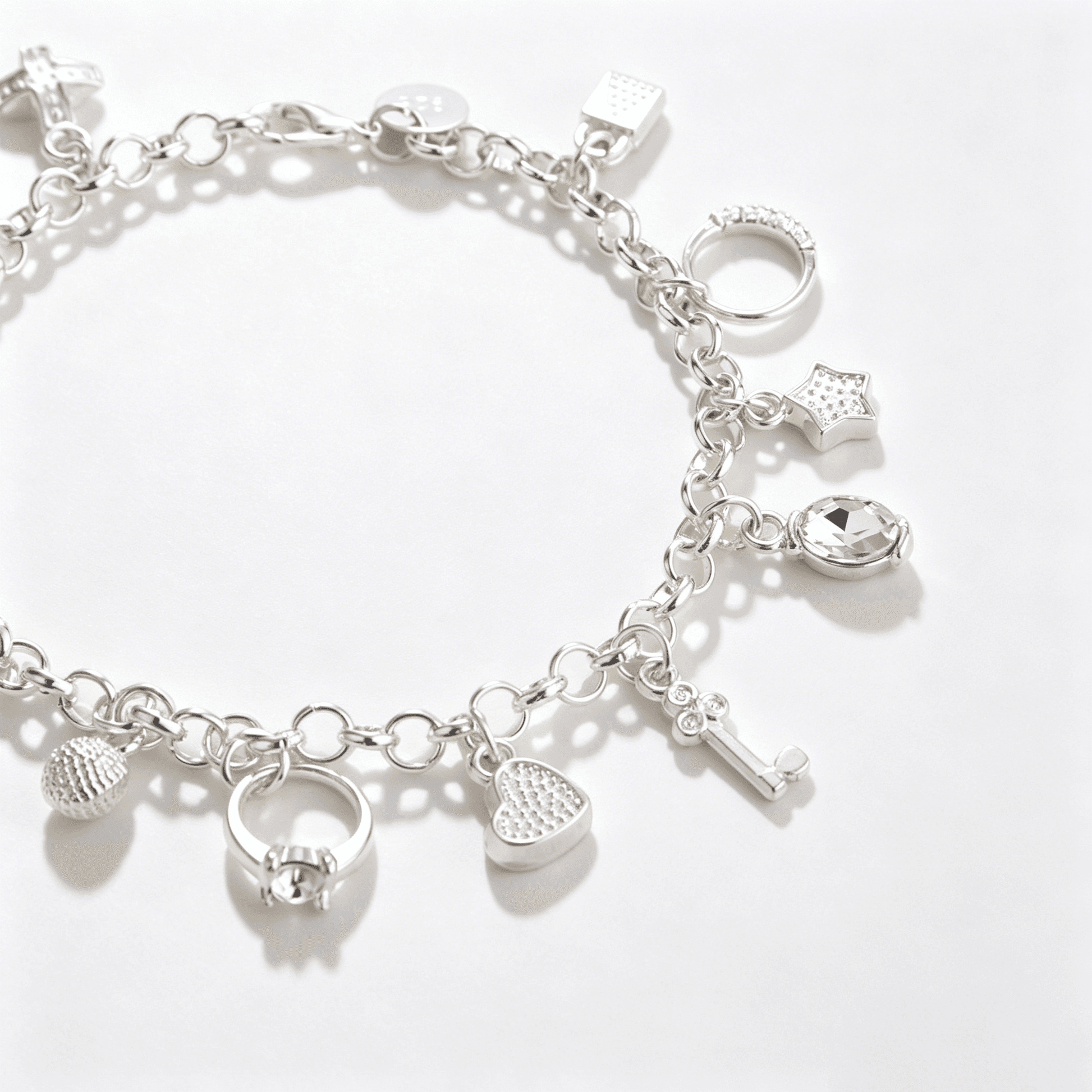 An angled view of a sterling silver charm bracelet for women adorned with multiple detailed pendants.