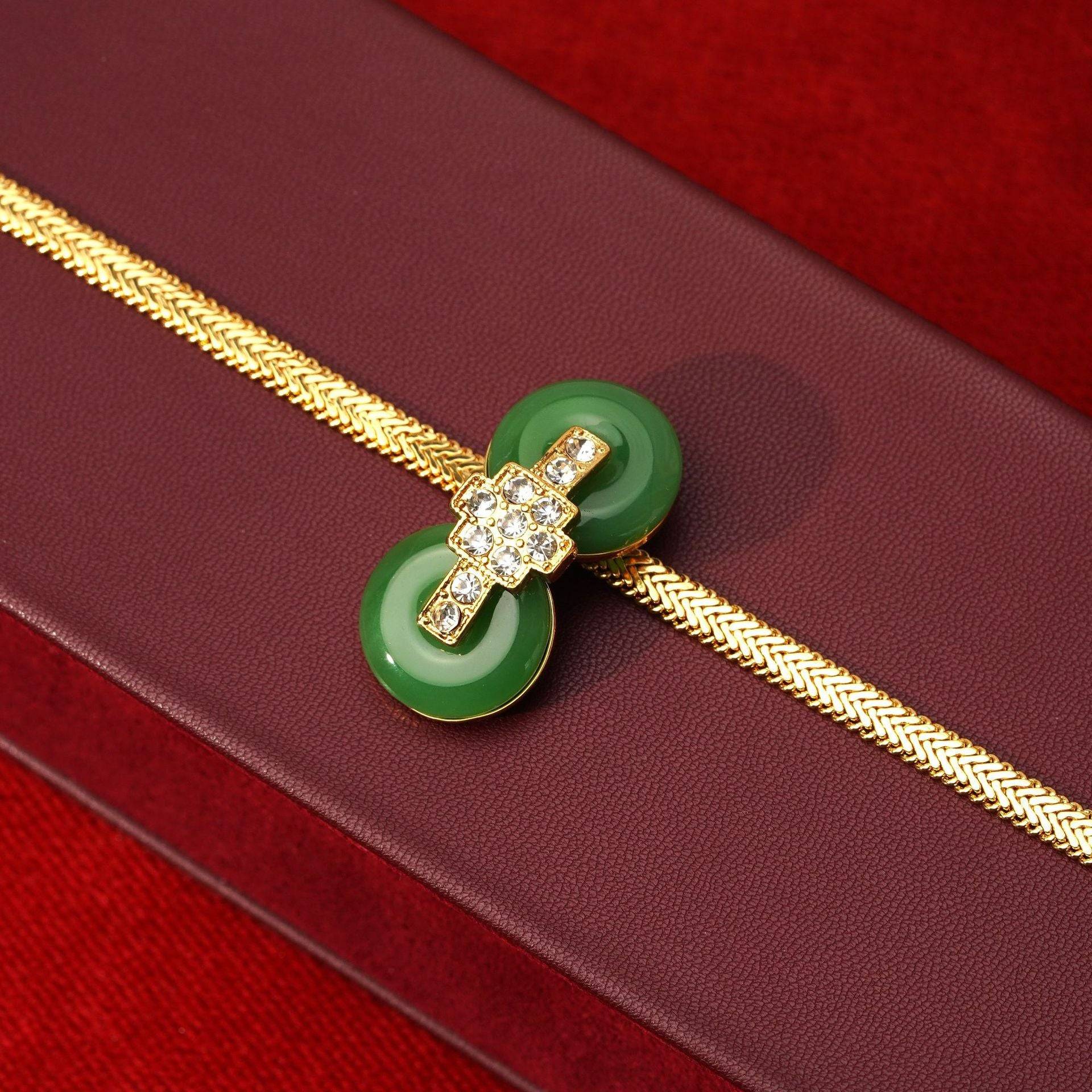 Detailed view of the geometric cross motif micro-paved with CZ crystals connecting the green crystal double donut discs on a gold herringbone chain.