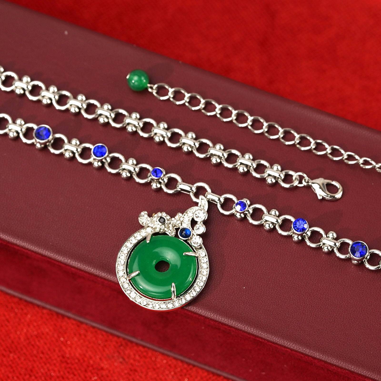 Micro texture of the premium link chain intricately inlaid with brilliant sapphire blue crystals next to a green glass bead dangle.