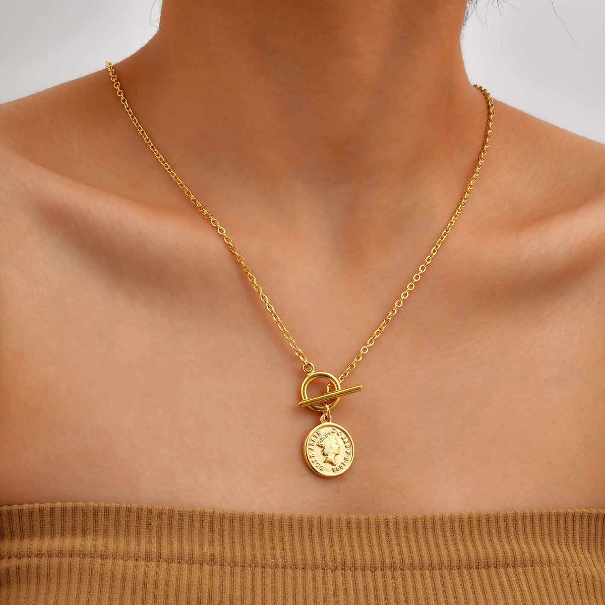 Front view of the coin pendant necklace styled with a simple top to show how the round charm sits on the chest.