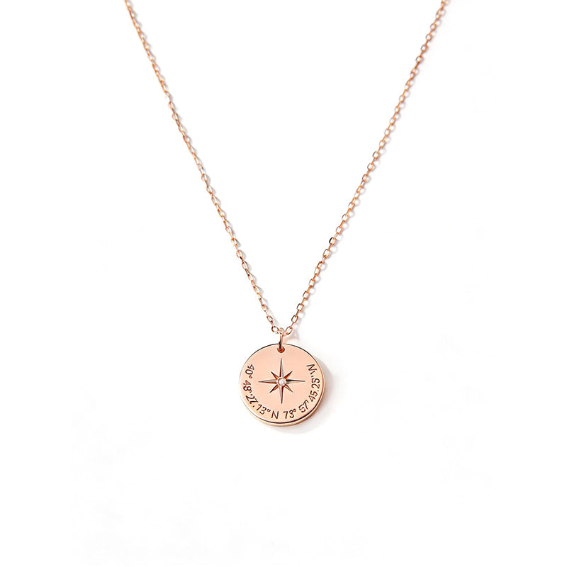 Rose gold-tone compass pendant showing a star motif and coordinate-style details around the disc.