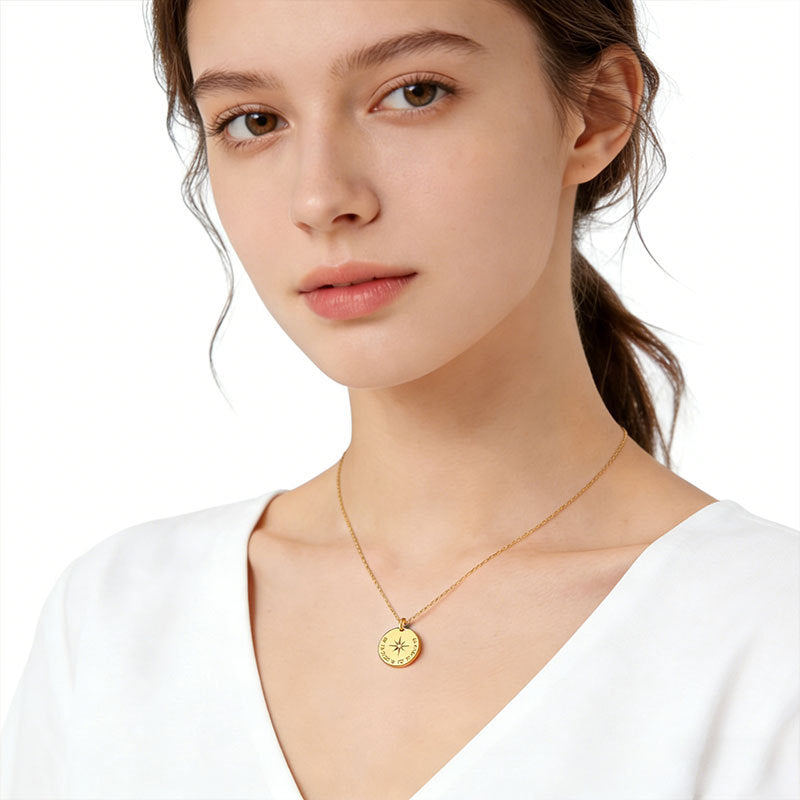 Woman wearing a gold-tone compass star pendant necklace with a white V-neck top.