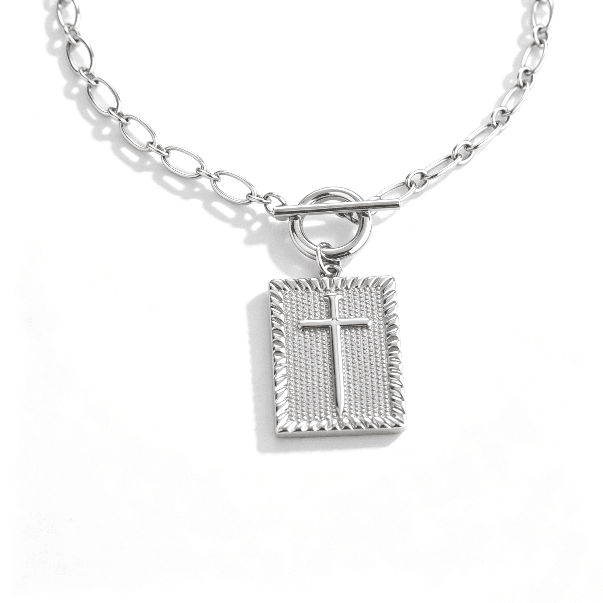 A minimalist silver cross necklace for women laid out to show the 3D square cross silhouette.