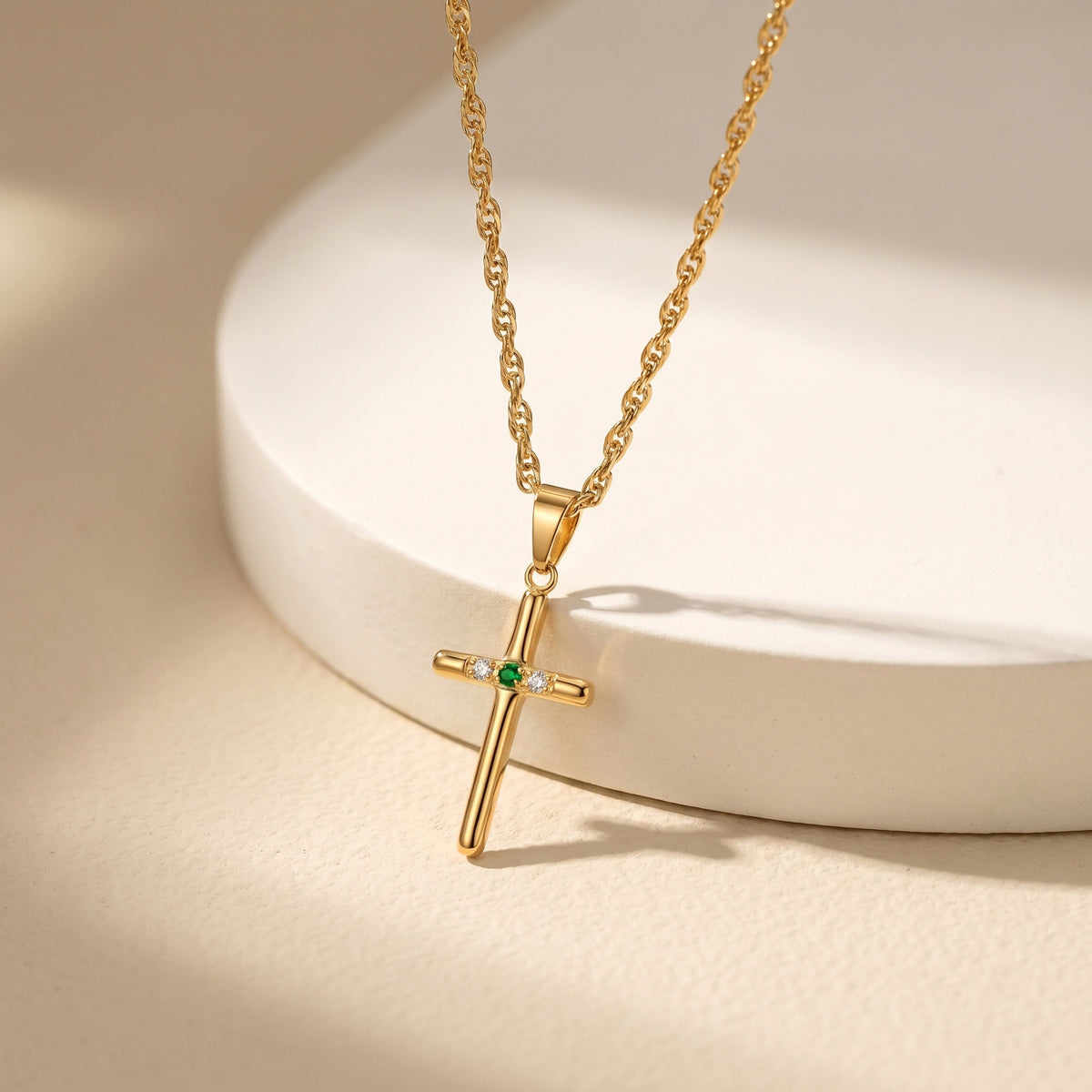Cross pendant necklace displayed on a light surface, showing the pendant and fine chain from the front.